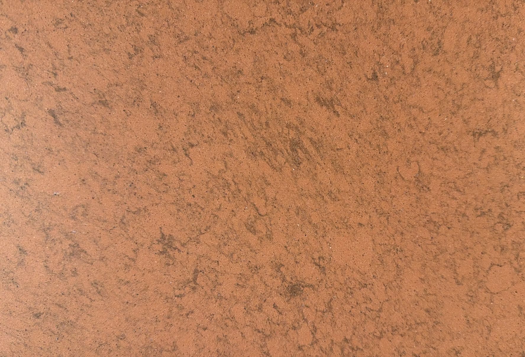 Close-up of a peach-colored textured surface with scattered dark speckles