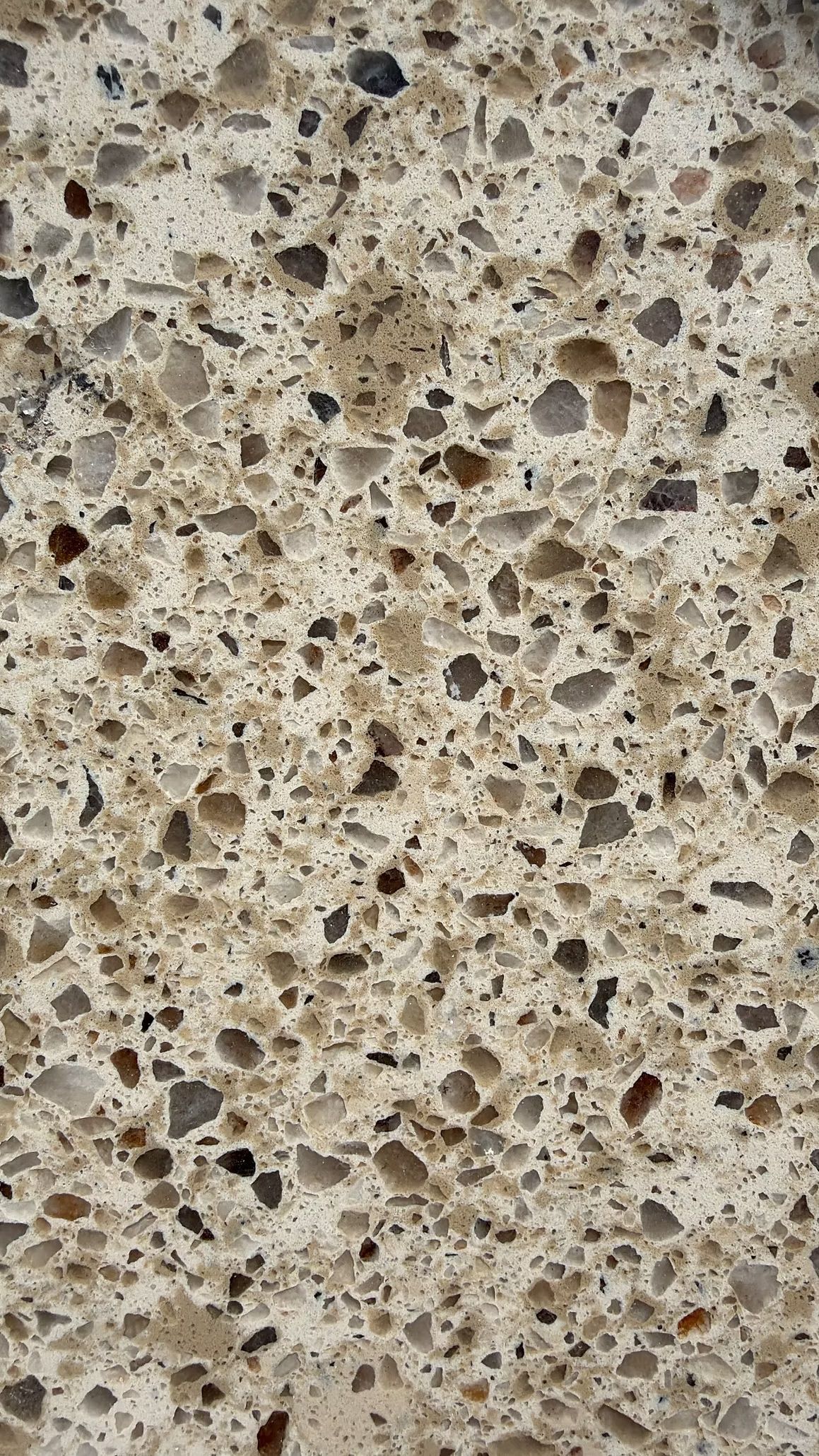 Close-up of a beige speckled stone or concrete surface with many small holes