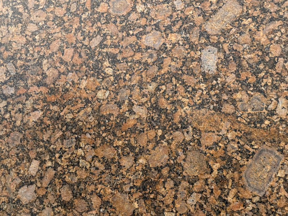 Brown and black speckled granite surface with a polished, mottled texture