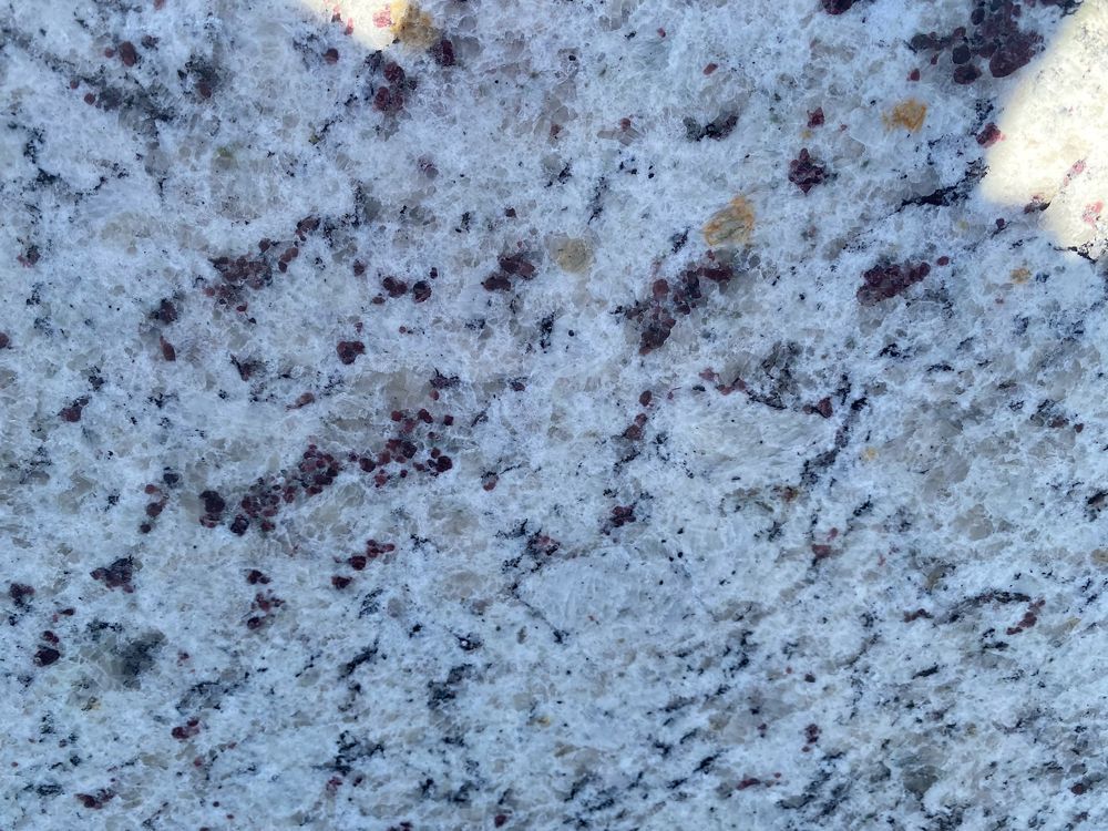 Close-up of a light blue speckled granite surface with dark and brown flecks