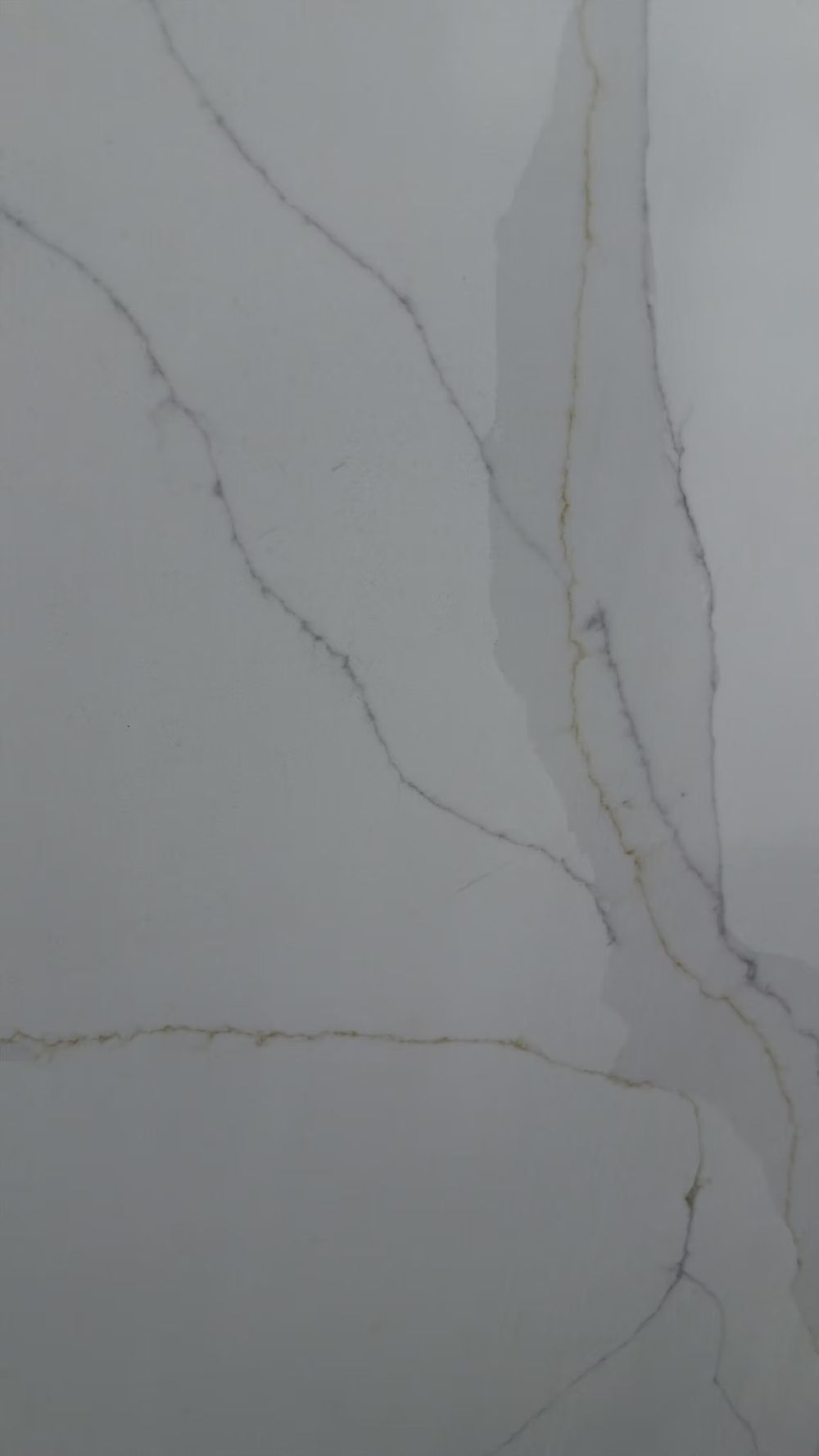White marble surface with thin gray veining and a vertical crack on the right side