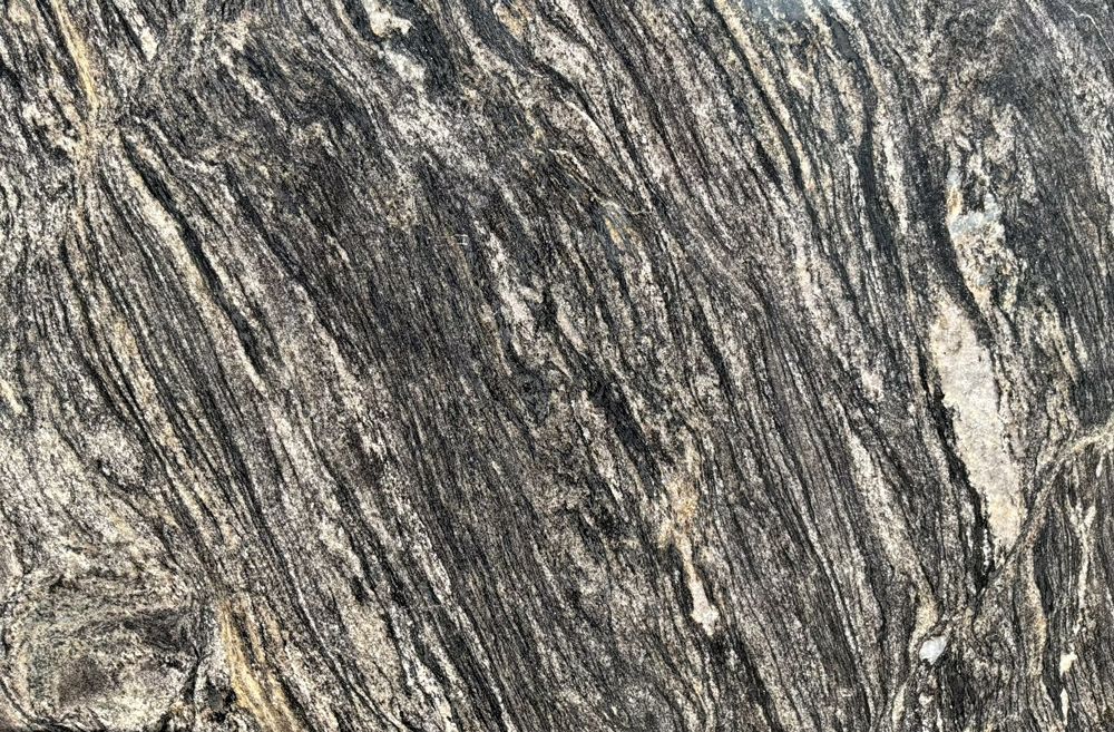 Close-up of gray and black streaked rock with a rough, layered texture.