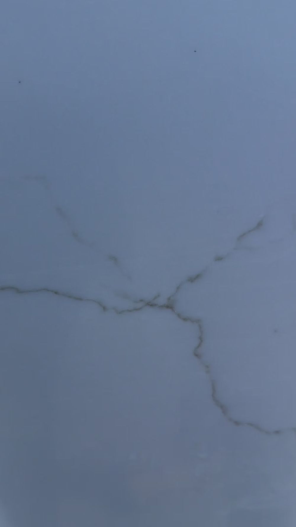 Cracked light gray wall with a branching hairline fracture near the center