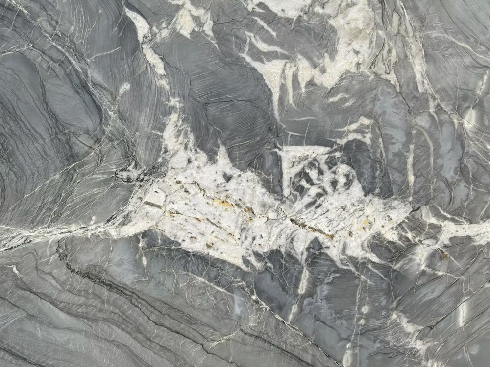 Aerial view of a gray rocky landscape with a light-colored quarry or mining site in the center