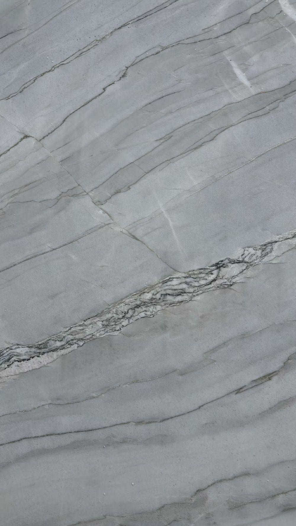 Close-up of white and gray marble with tan veins and natural cracks