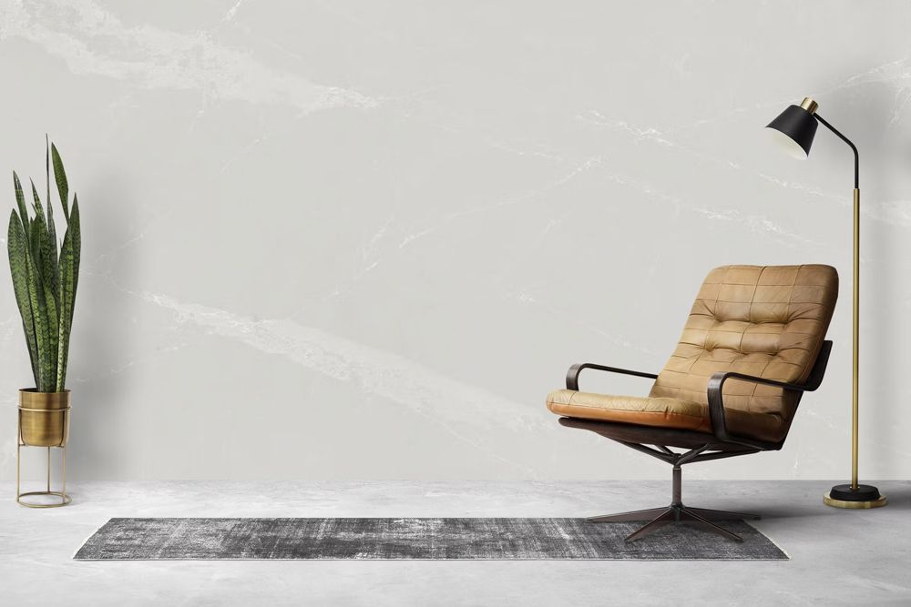 Minimalist living room with tan lounge chair, black floor lamp, rug, and tall potted plant against a gray wall