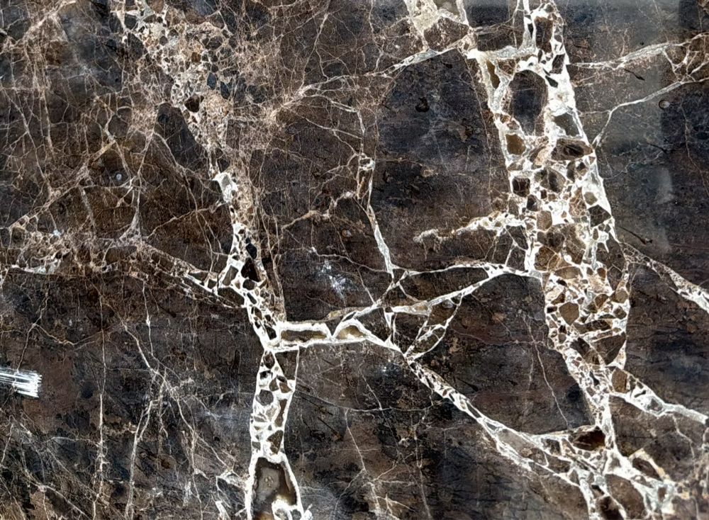 Close-up of dark brown marble with white veining and cracked patterns