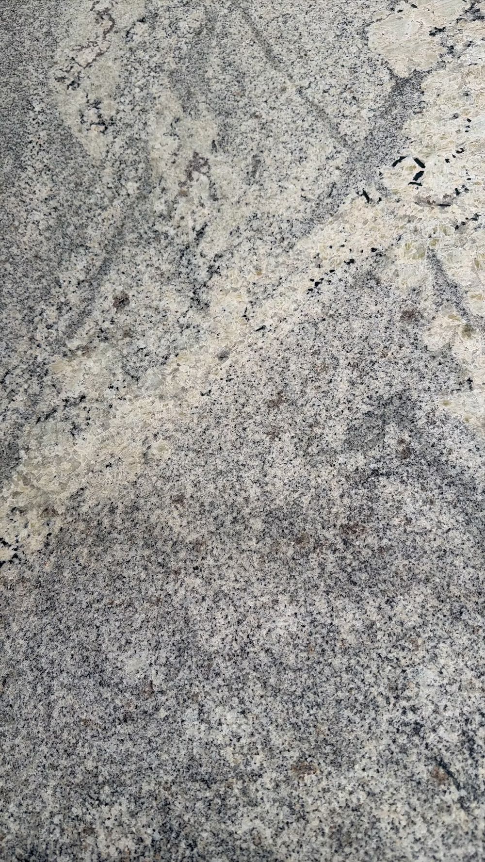 Close-up of a gray, speckled stone or granite surface with diagonal light and dark veining.