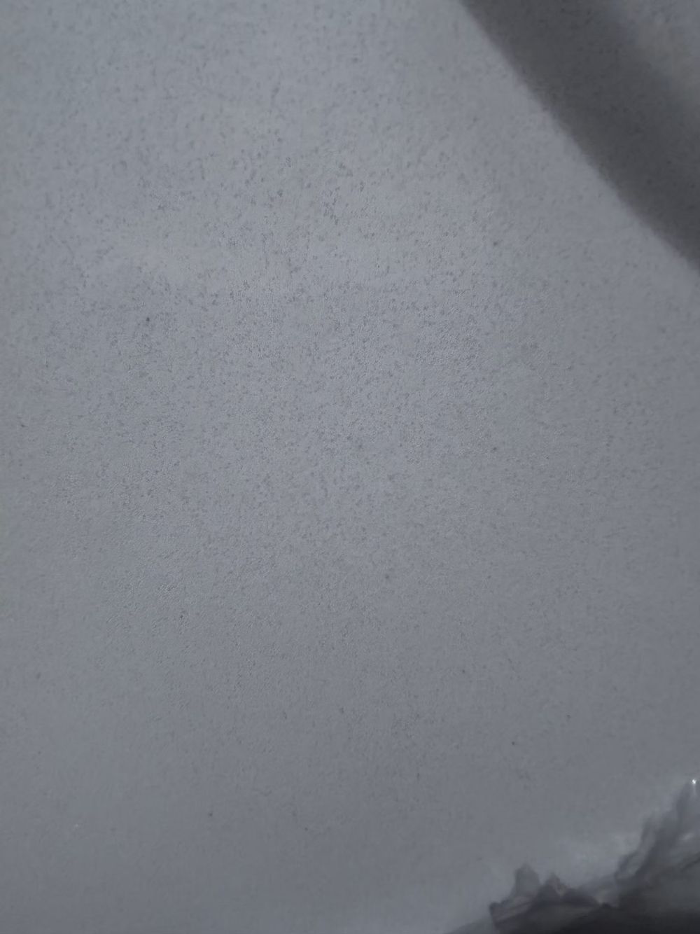 Close-up of a plain gray surface with a dark shadow in the corner