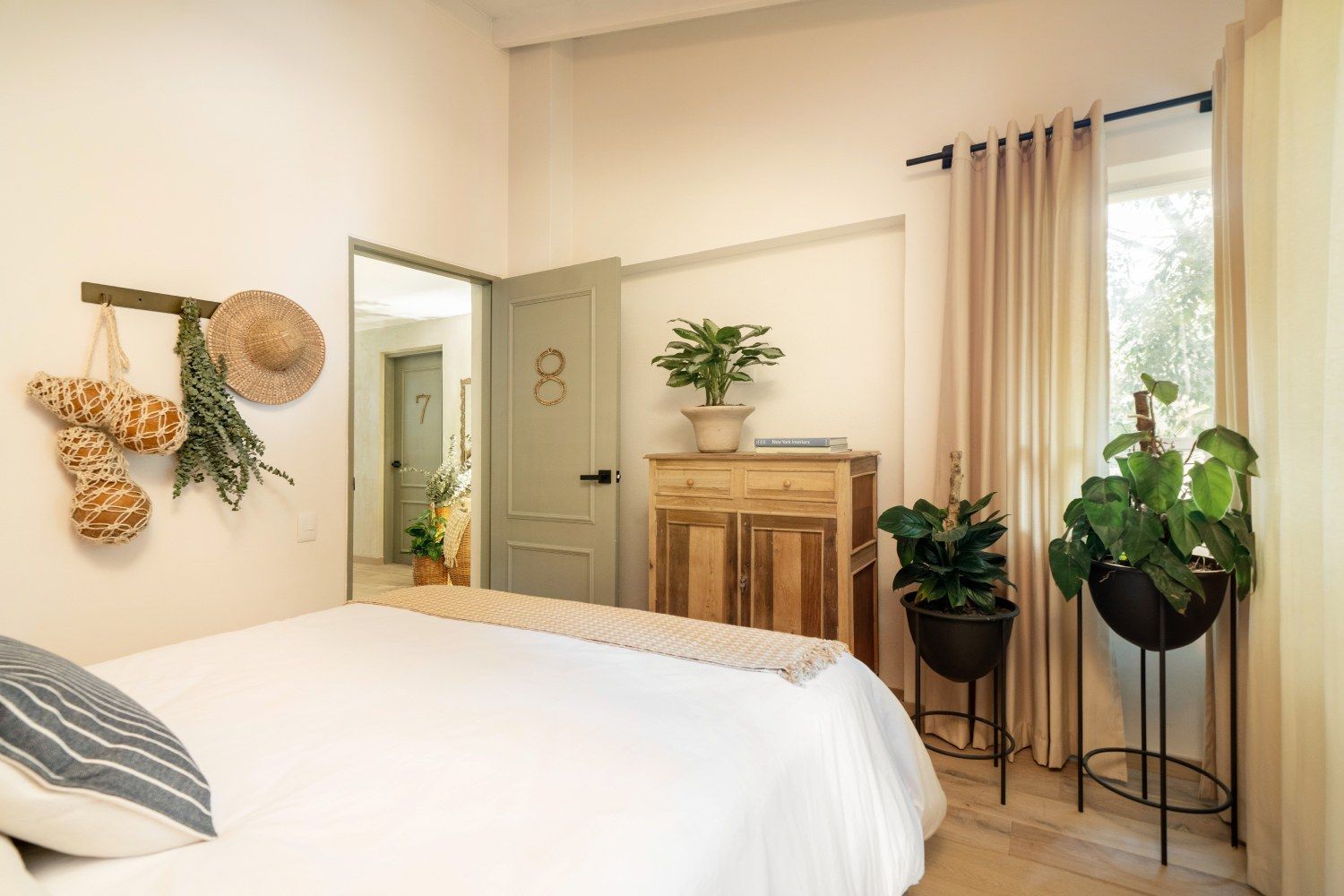 A bedroom with a bed , dresser , and potted plants.
