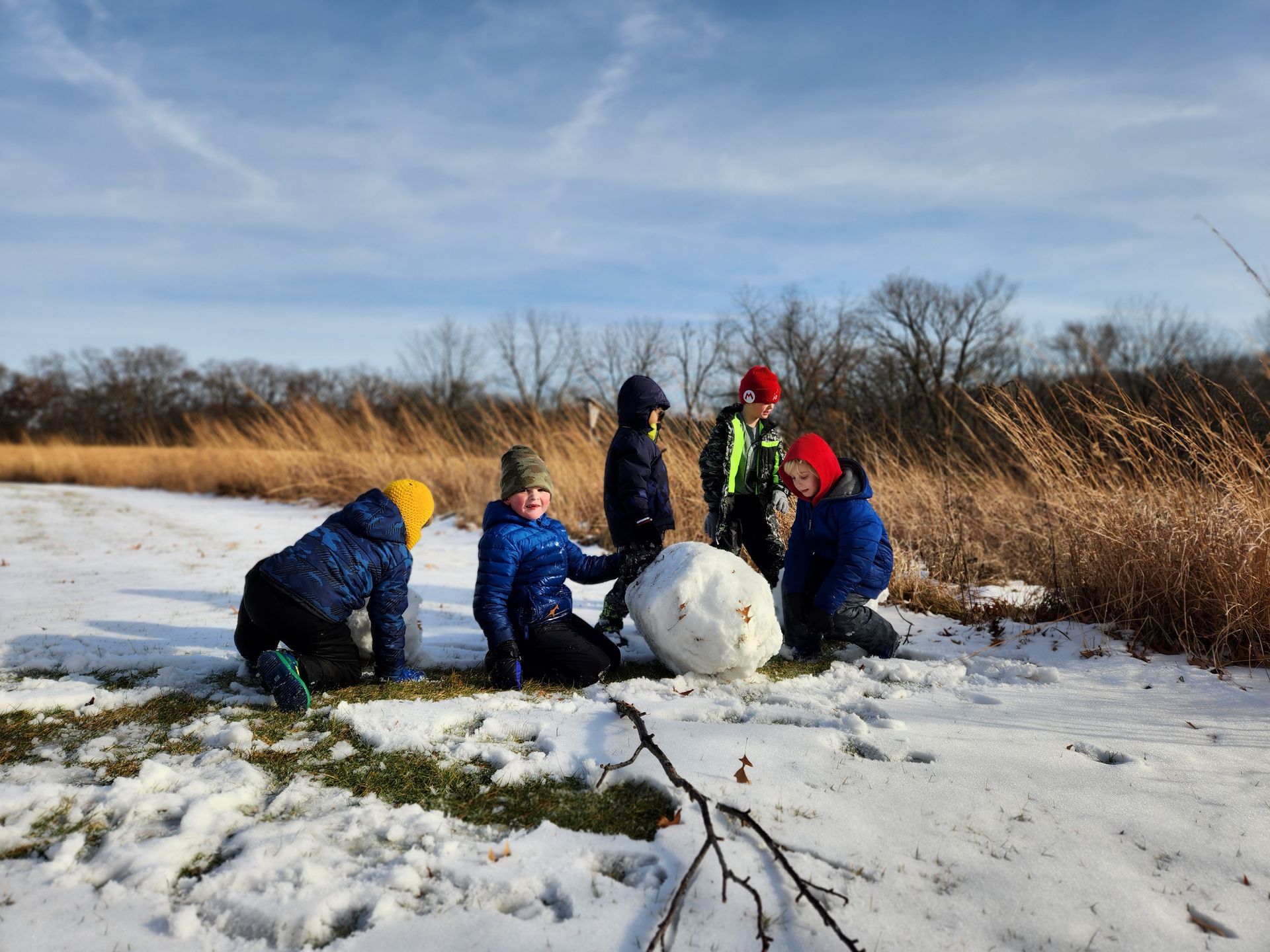 Children building a snowman in the prairie.