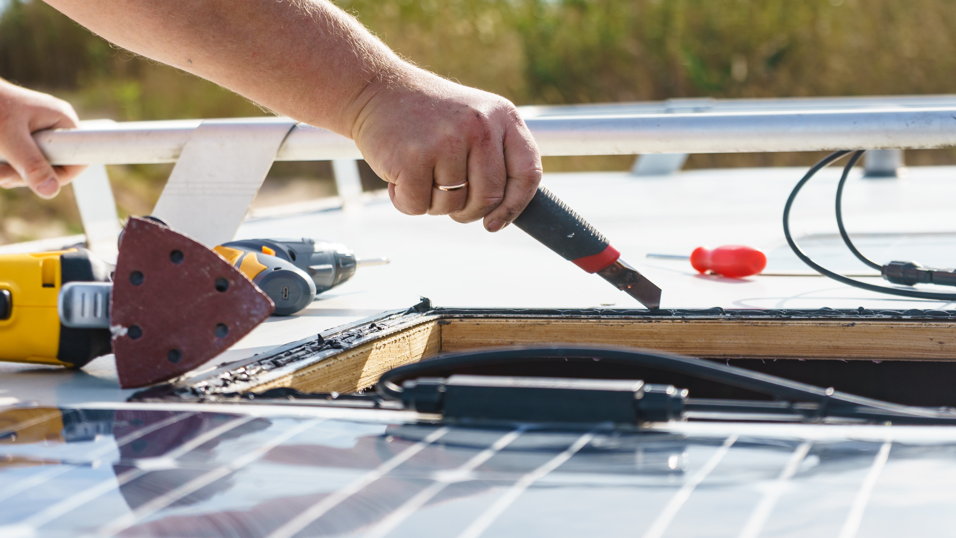 A person is sanding a solar panel with a sander.