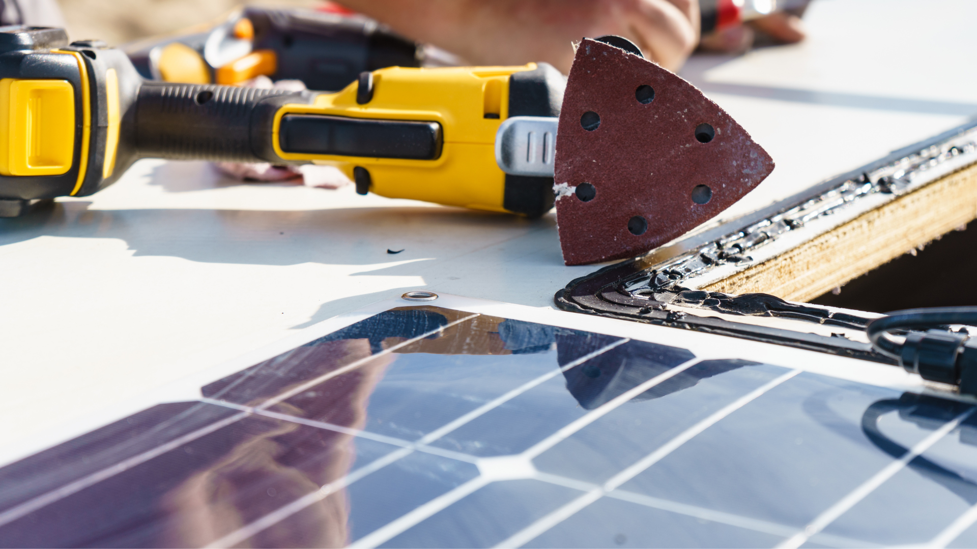 A person is working on a solar panel with a drill and sander.