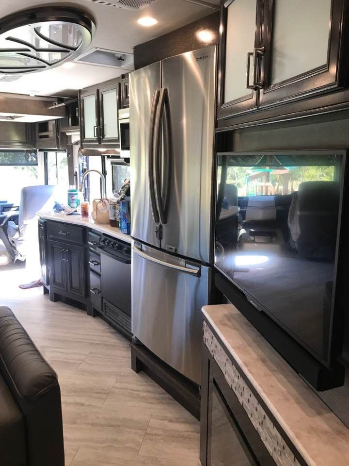 A kitchen with stainless steel appliances and a flat screen tv.