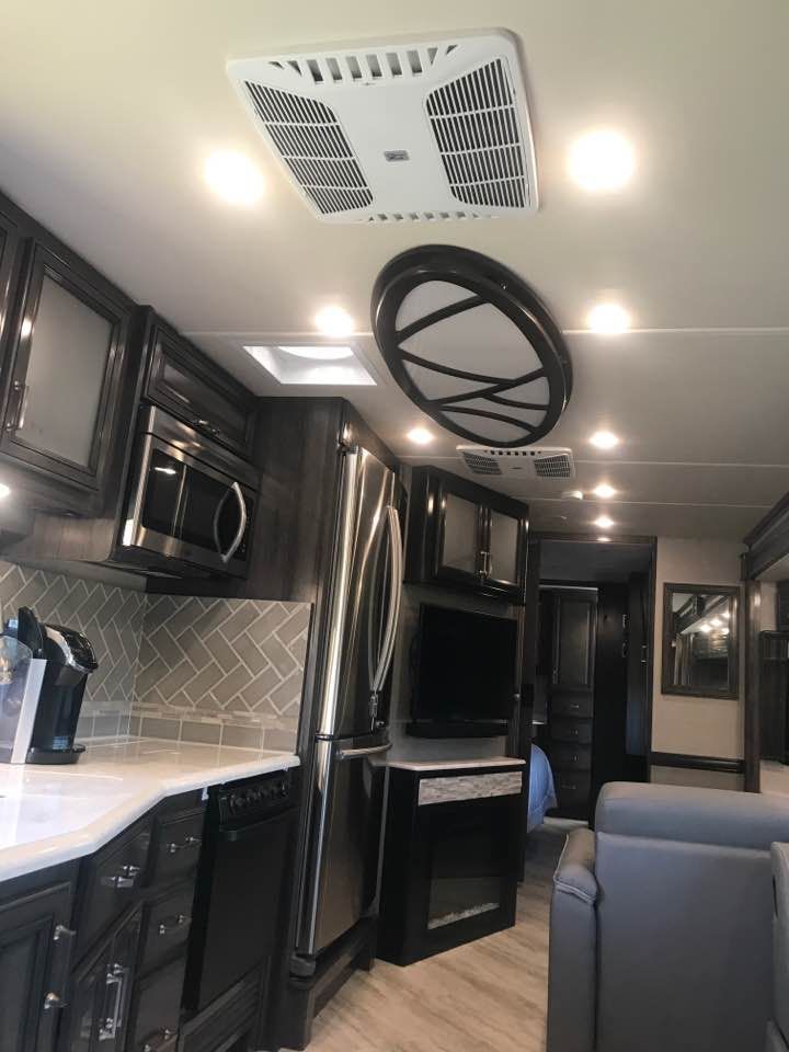A kitchen in a rv with stainless steel appliances and a fan on the ceiling.
