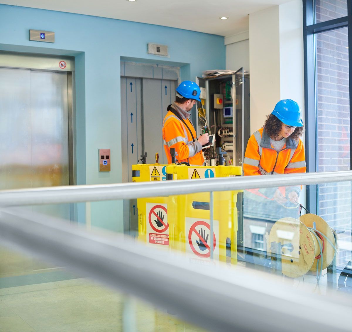 A man and a woman are working on an elevator in a building