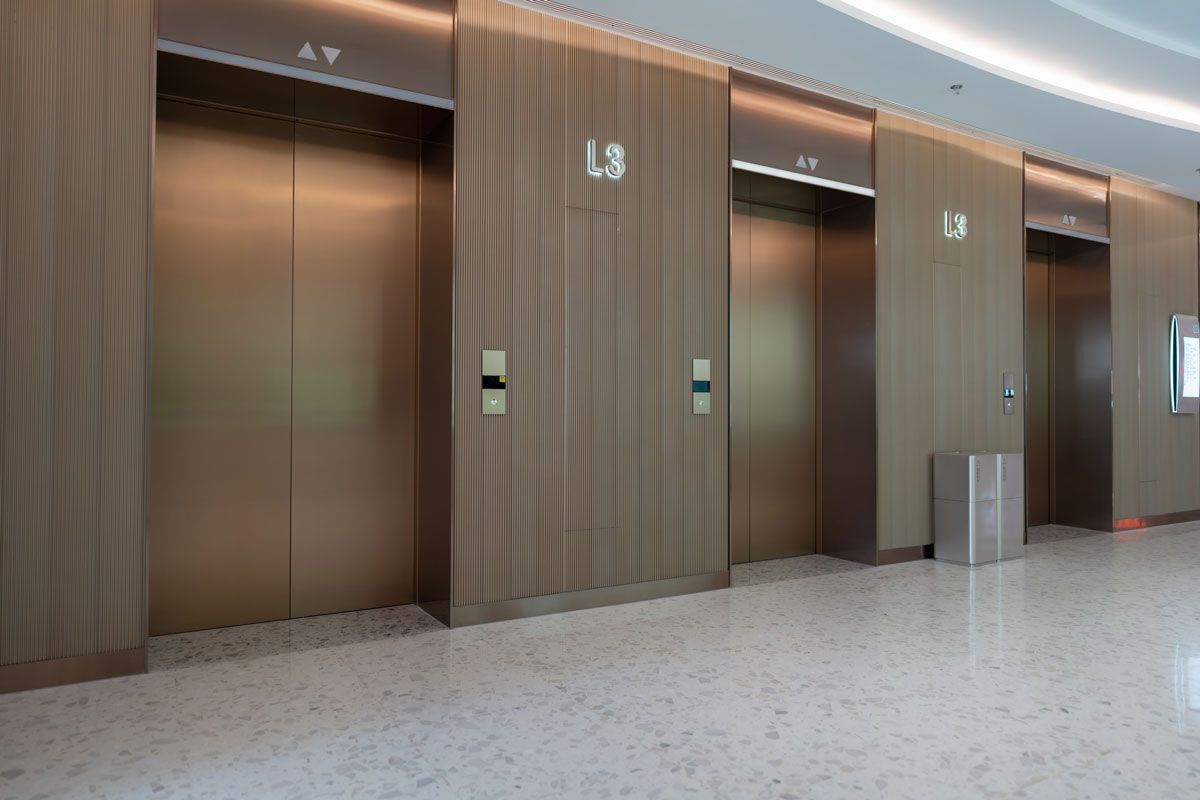 A row of elevators in a building with wooden walls.