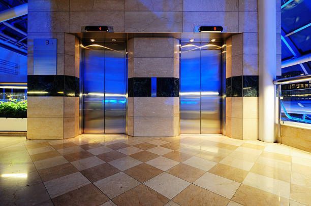 An empty lobby with two elevators and a checkered floor.