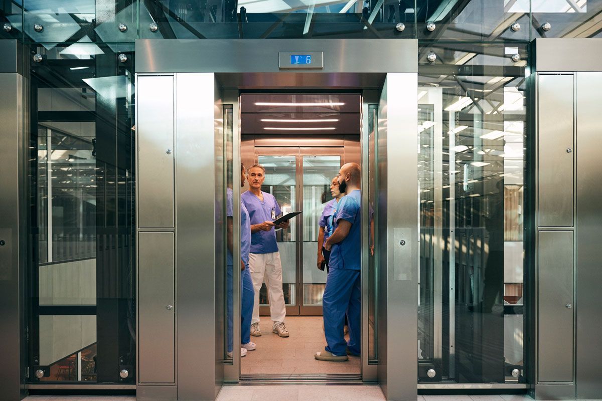 Two nurses are standing in an elevator in a hospital.