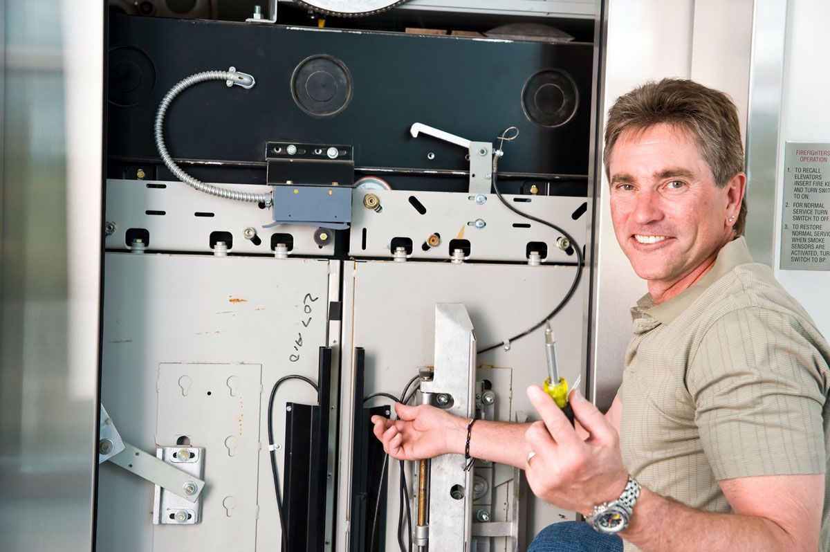 A man is working on an elevator with a screwdriver