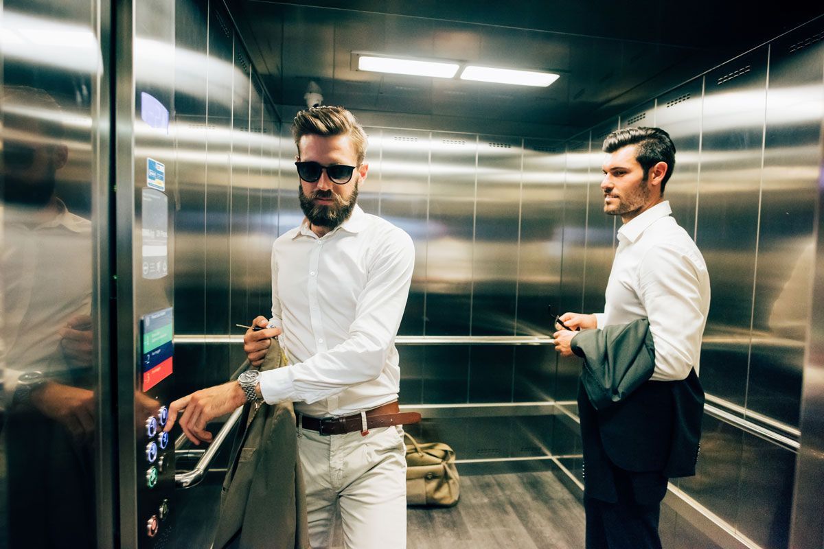 Two men are standing in an elevator.