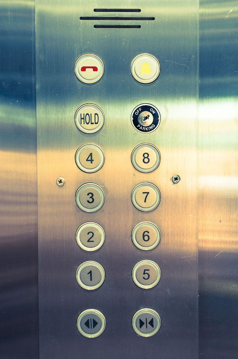 A close up of a stainless steel elevator control panel