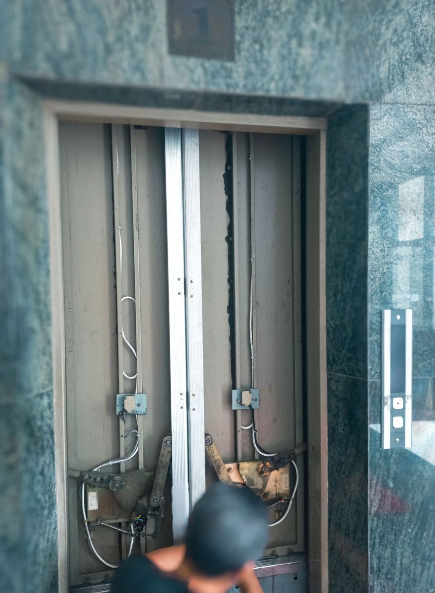 A man is standing in an elevator with the doors open.