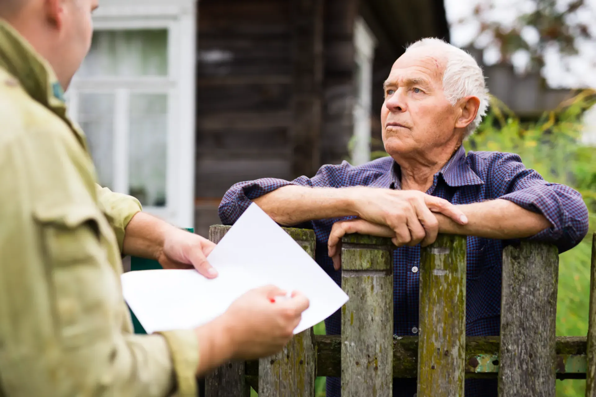 man and neighbor standing by a wooden fence