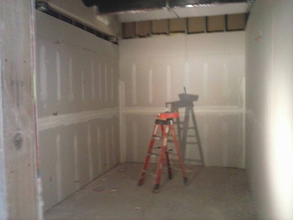 Unfinished drywall room with a red ladder and a work light on the floor