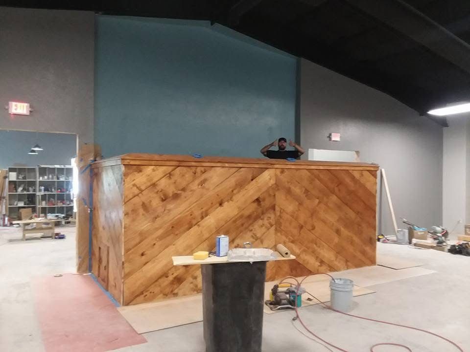 Wood-paneled booth in a warehouse, with a person working behind the counter and a small table in front
