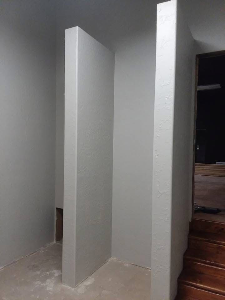 Unfinished interior hallway with two white partition walls beside wooden stairs.