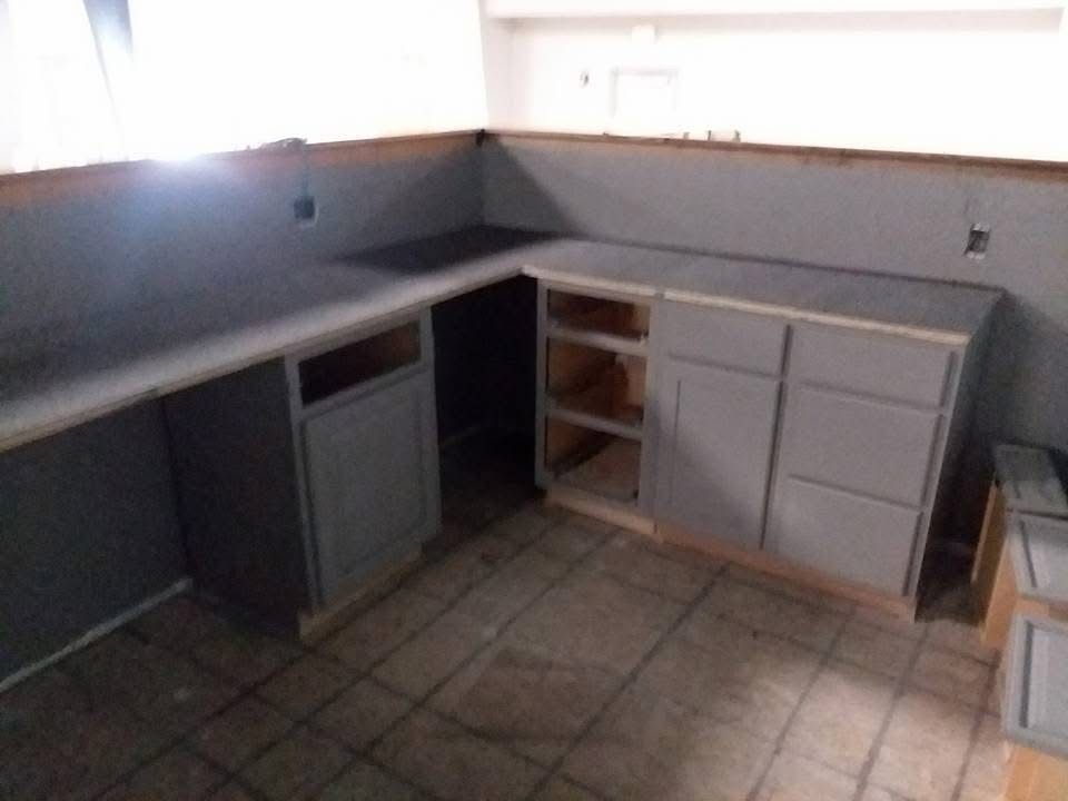 Empty kitchen corner with gray cabinets, tiled floor, and a small under-counter fridge.