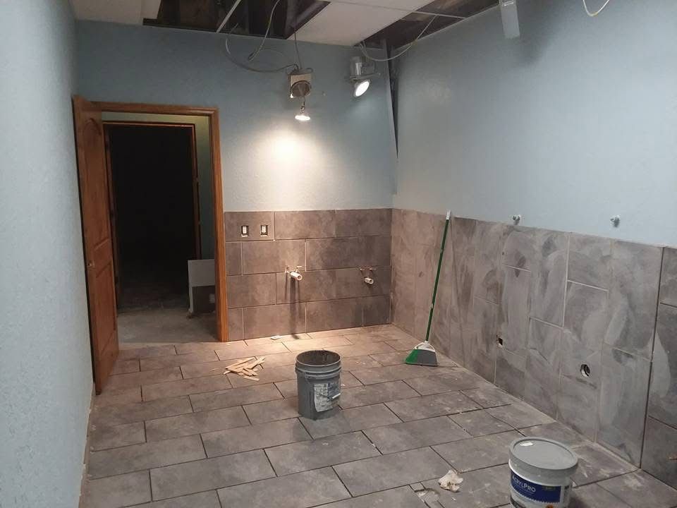 Partially renovated room with tiled floor, blue walls, and paint buckets on the ground