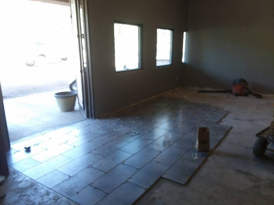 Partially tiled room with a doorway, windows, and construction tools on the floor