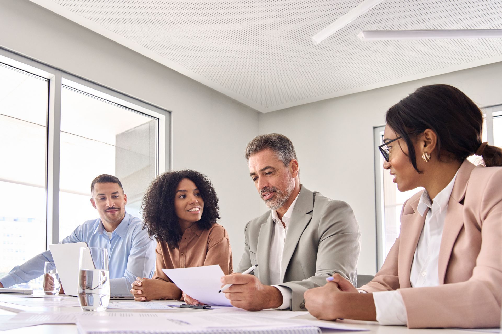 A group of people are sitting at a table in a conference room having a meeting.