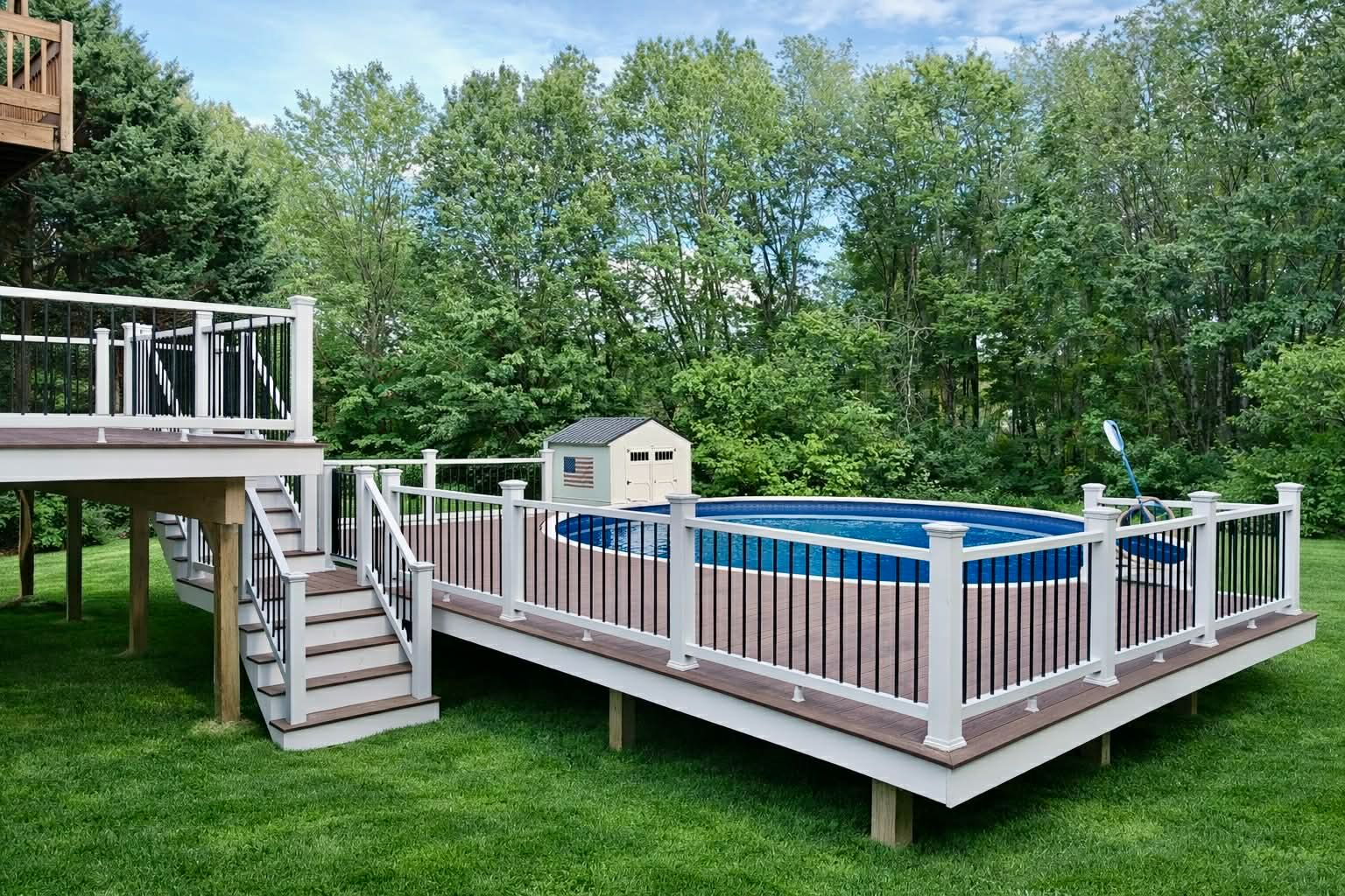 Backyard above-ground pool with wooden deck, white railing, and steps surrounded by green trees