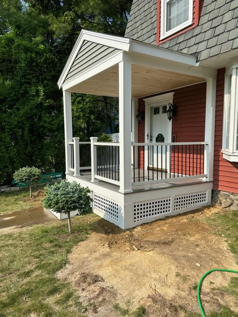 A red house with a white porch and a green hose in front of it - Plaistow, NH - Dynamic Deck Solutions