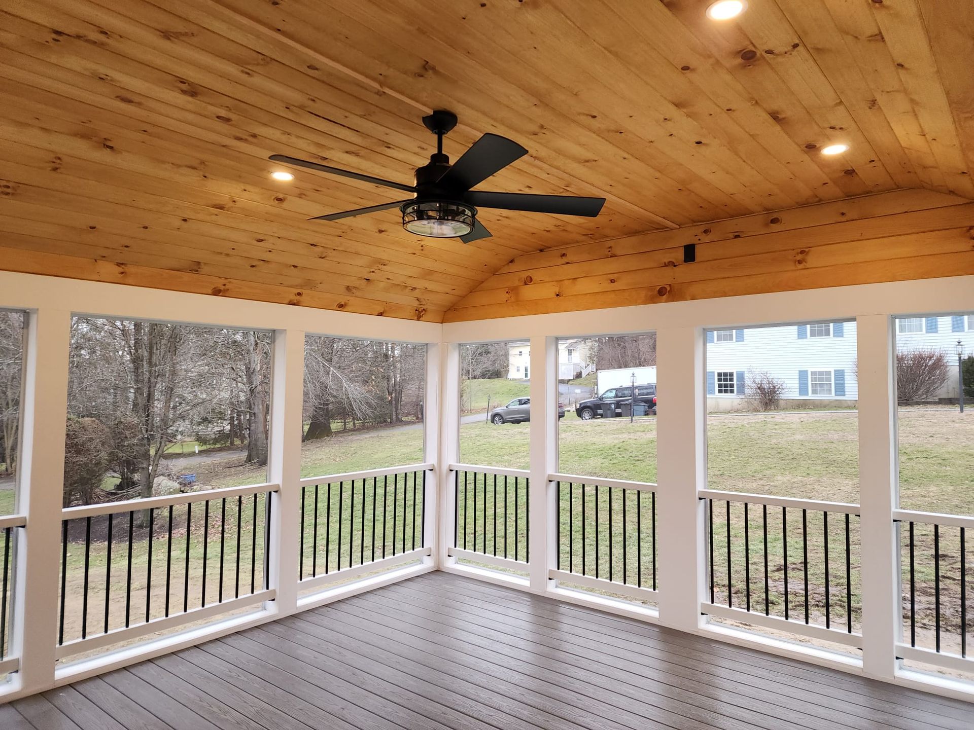 A screened in porch with a ceiling fan and lots of windows - Plaistow, NH - Dynamic Deck Solutions