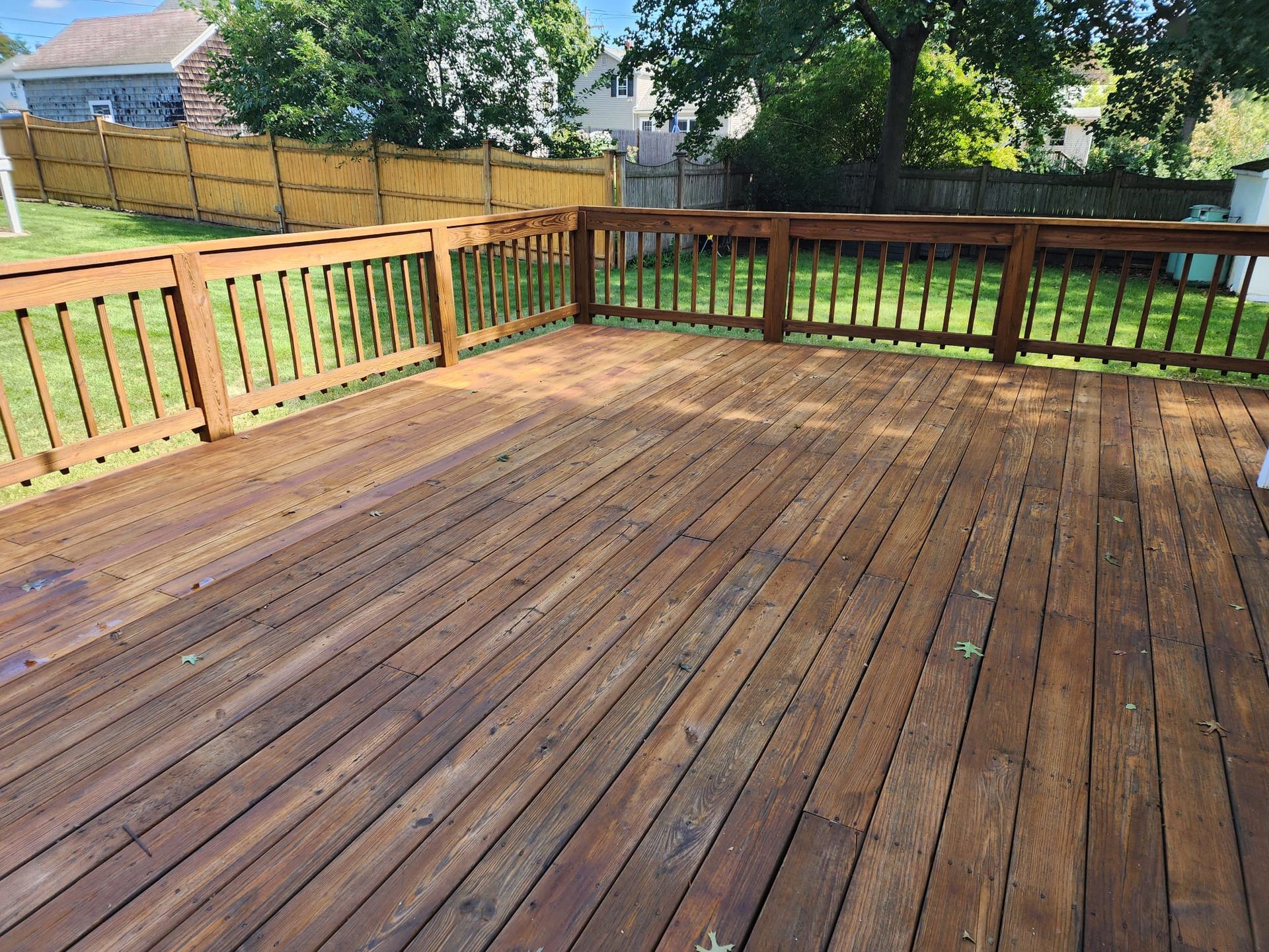 A large wooden deck with a fence in the backyard - Plaistow, NH - Dynamic Deck Solutions