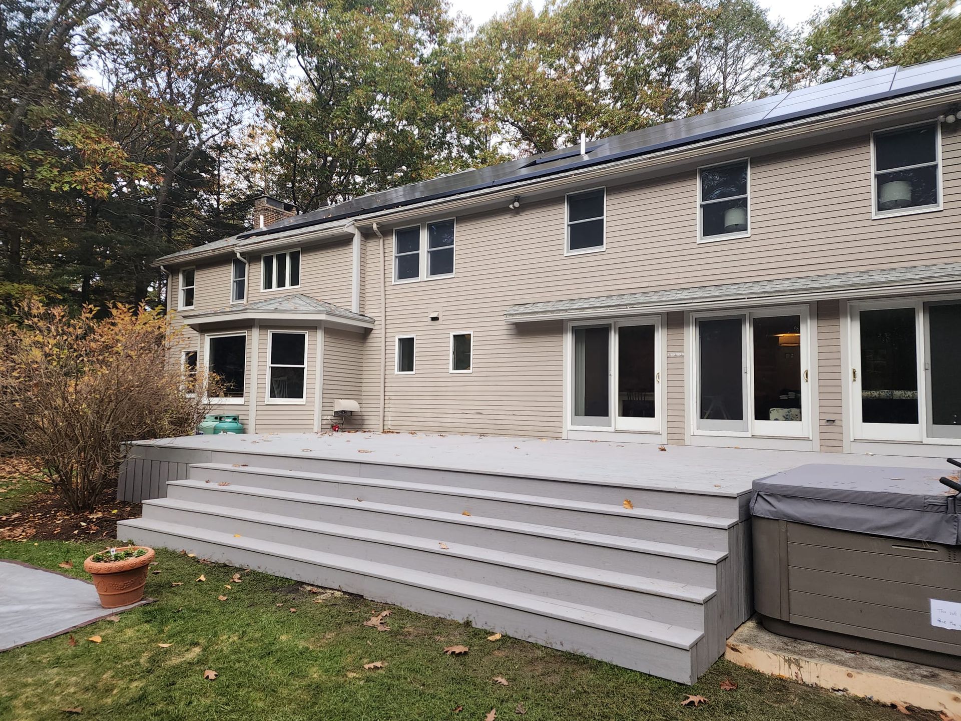 A large house with a deck and stairs in front of it - Plaistow, NH - Dynamic Deck Solutions