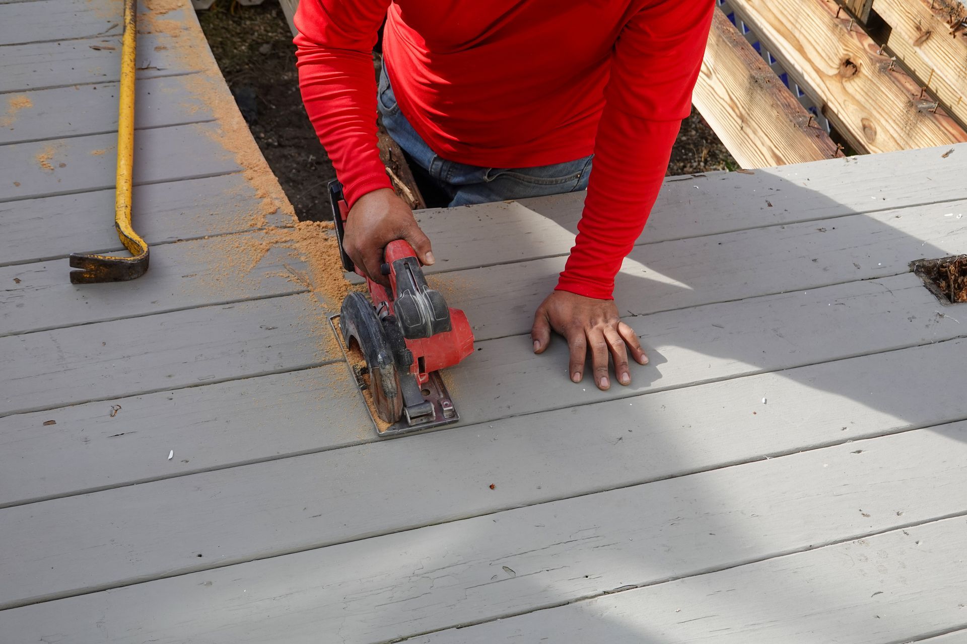 A deck builder cutting wooden planks with a circular saw.
