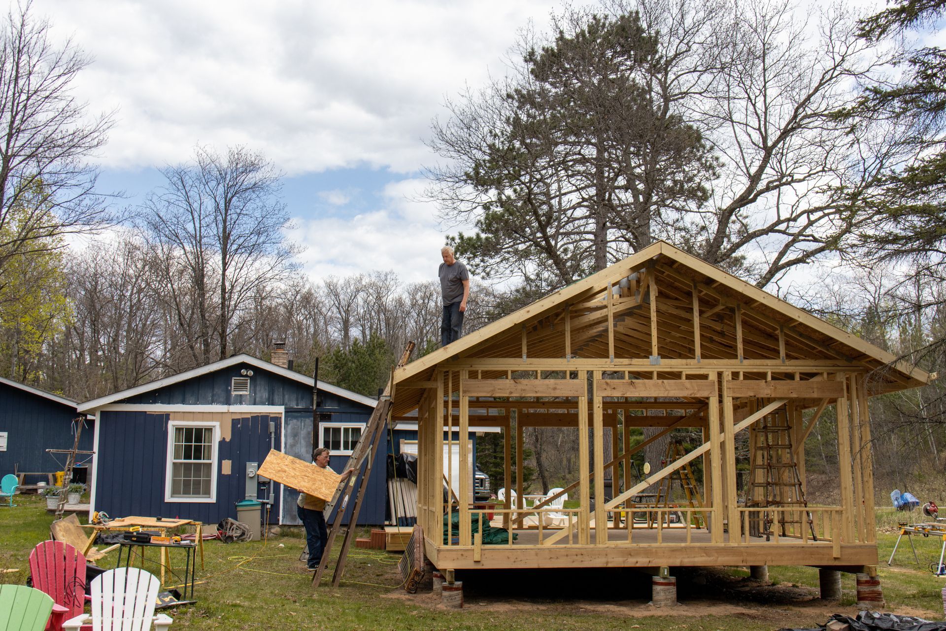 Sunroom contractor building wooden frame structure on backyard addition project with workers.