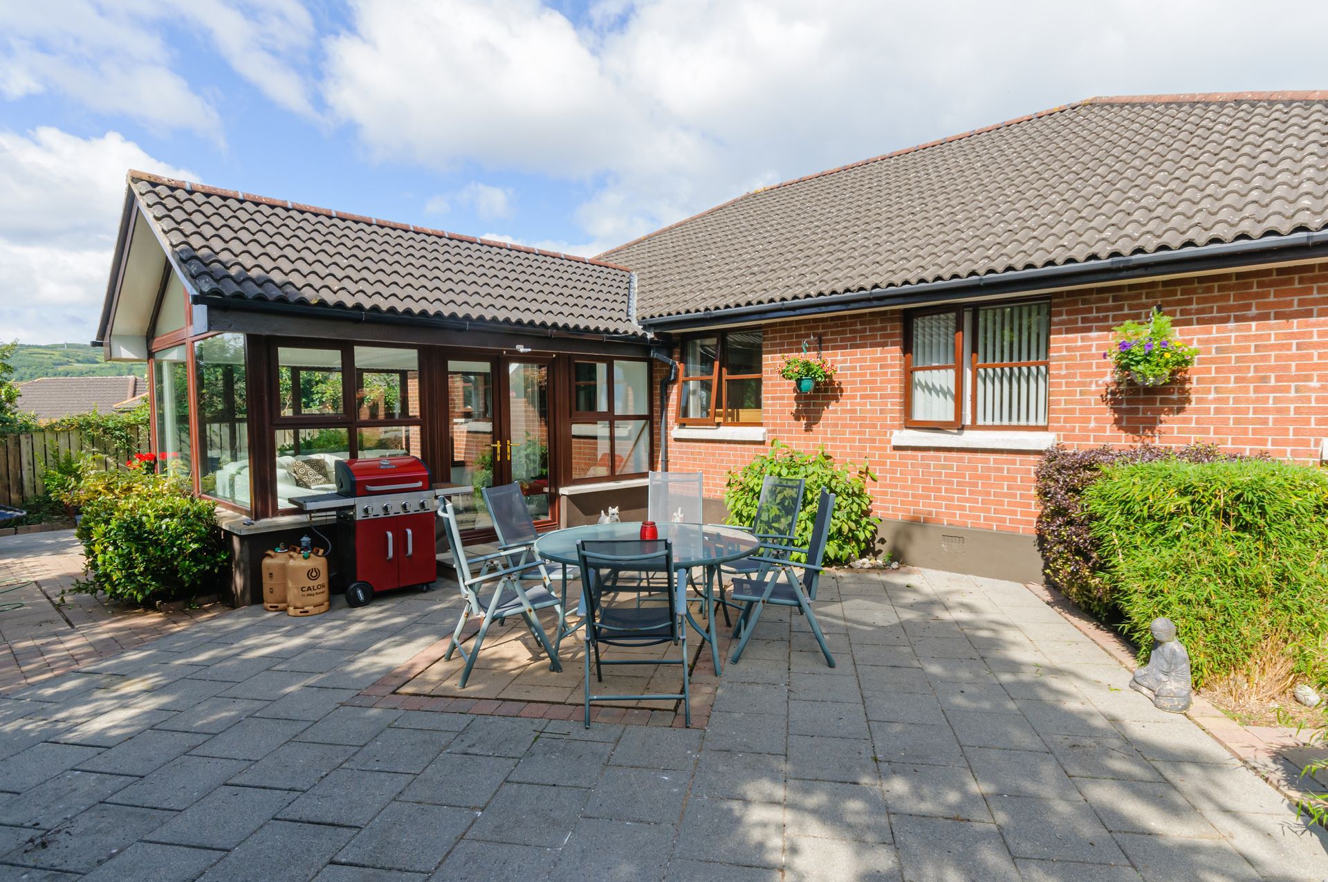 Brick home with a paved patio, outdoor dining set, and barbecue grill.