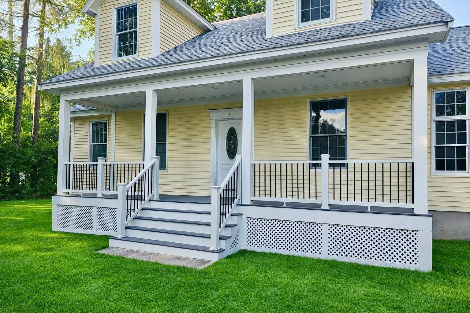 Yellow house with white porch, steps, and lattice skirting on a green lawn