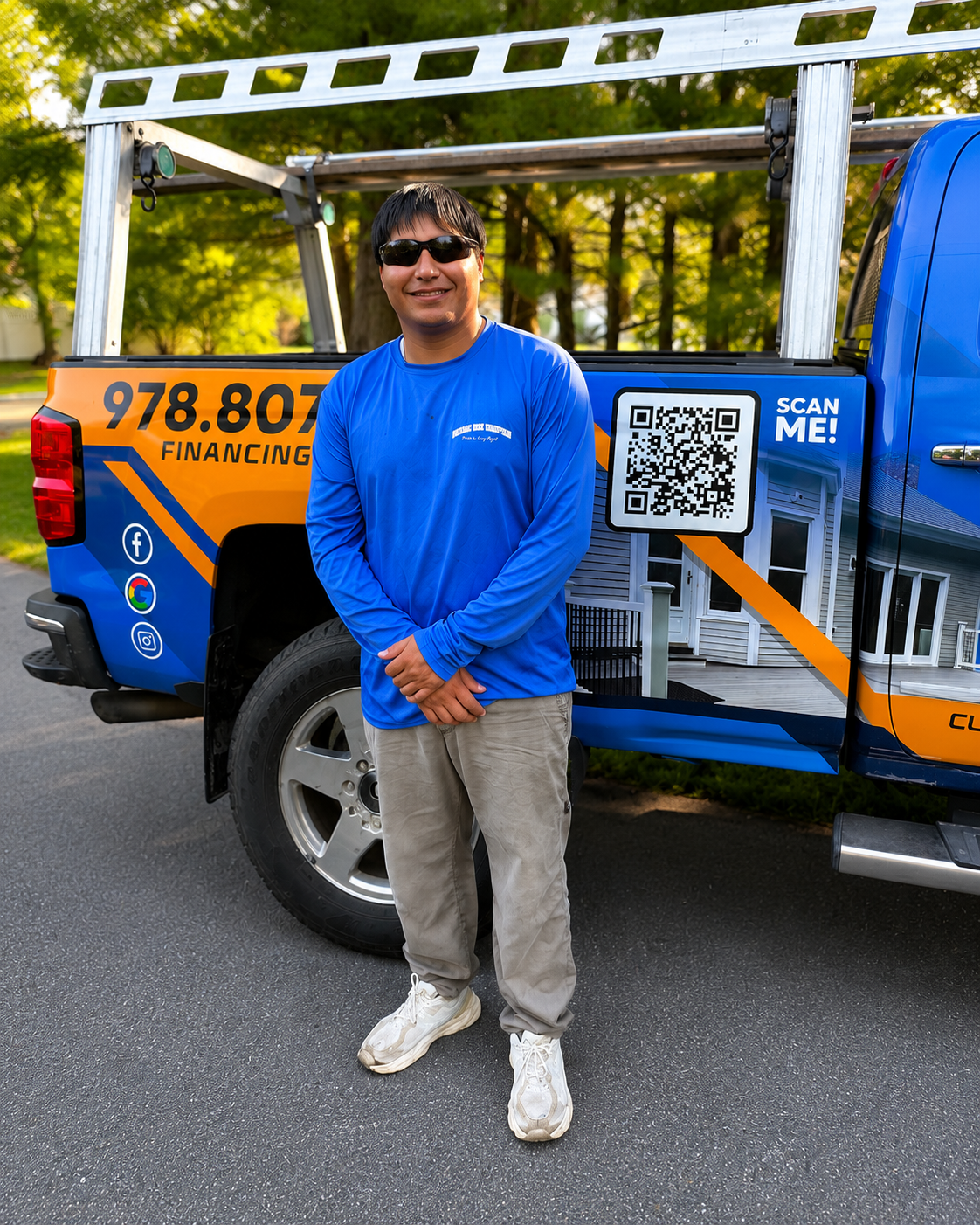 Man standing in front of a colorful utility truck with QR code graphics, wearing sunglasses and blue shirt.