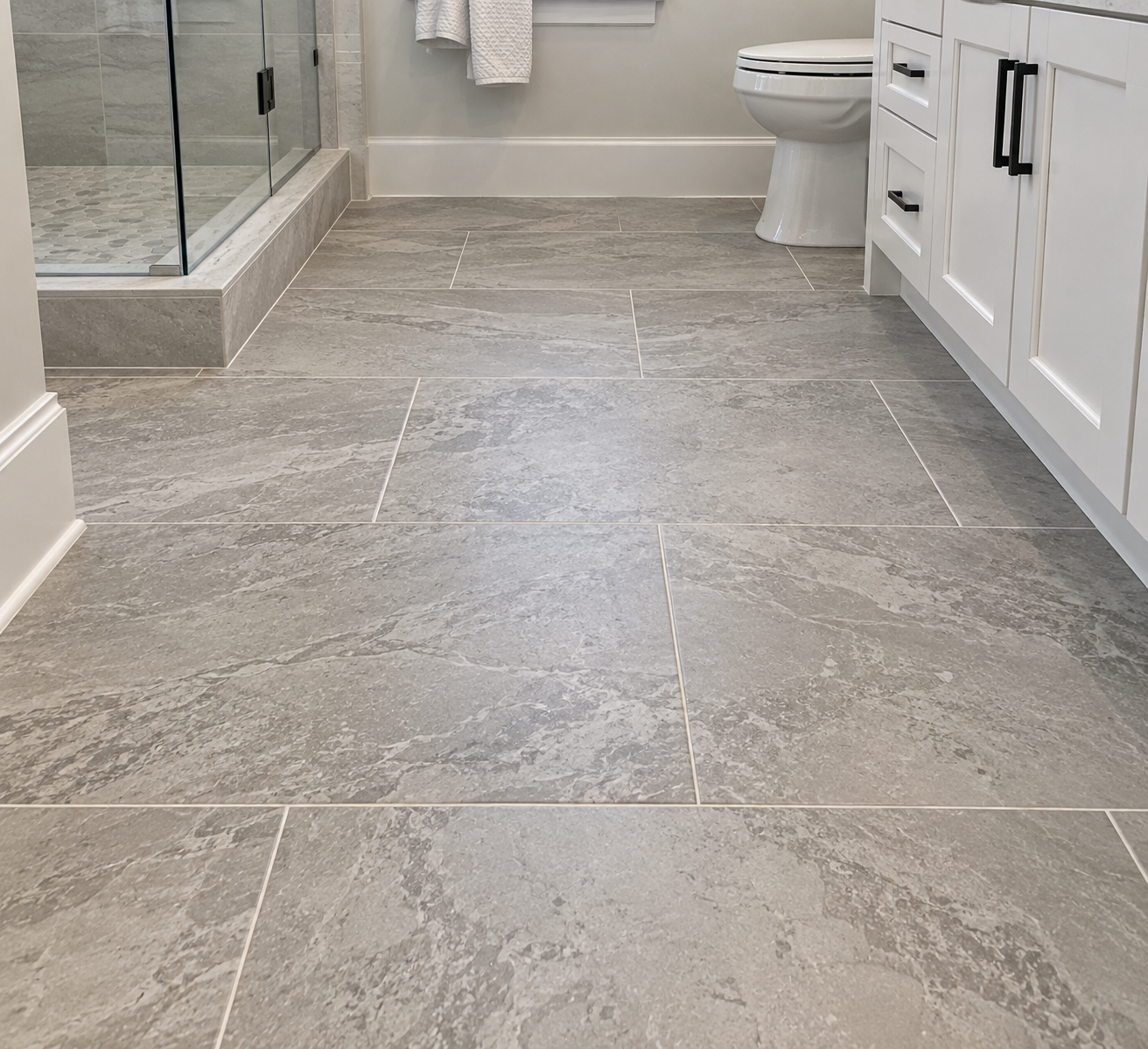 Accessible bathroom with white tile floor, wall-mounted sink, and glass shower enclosure