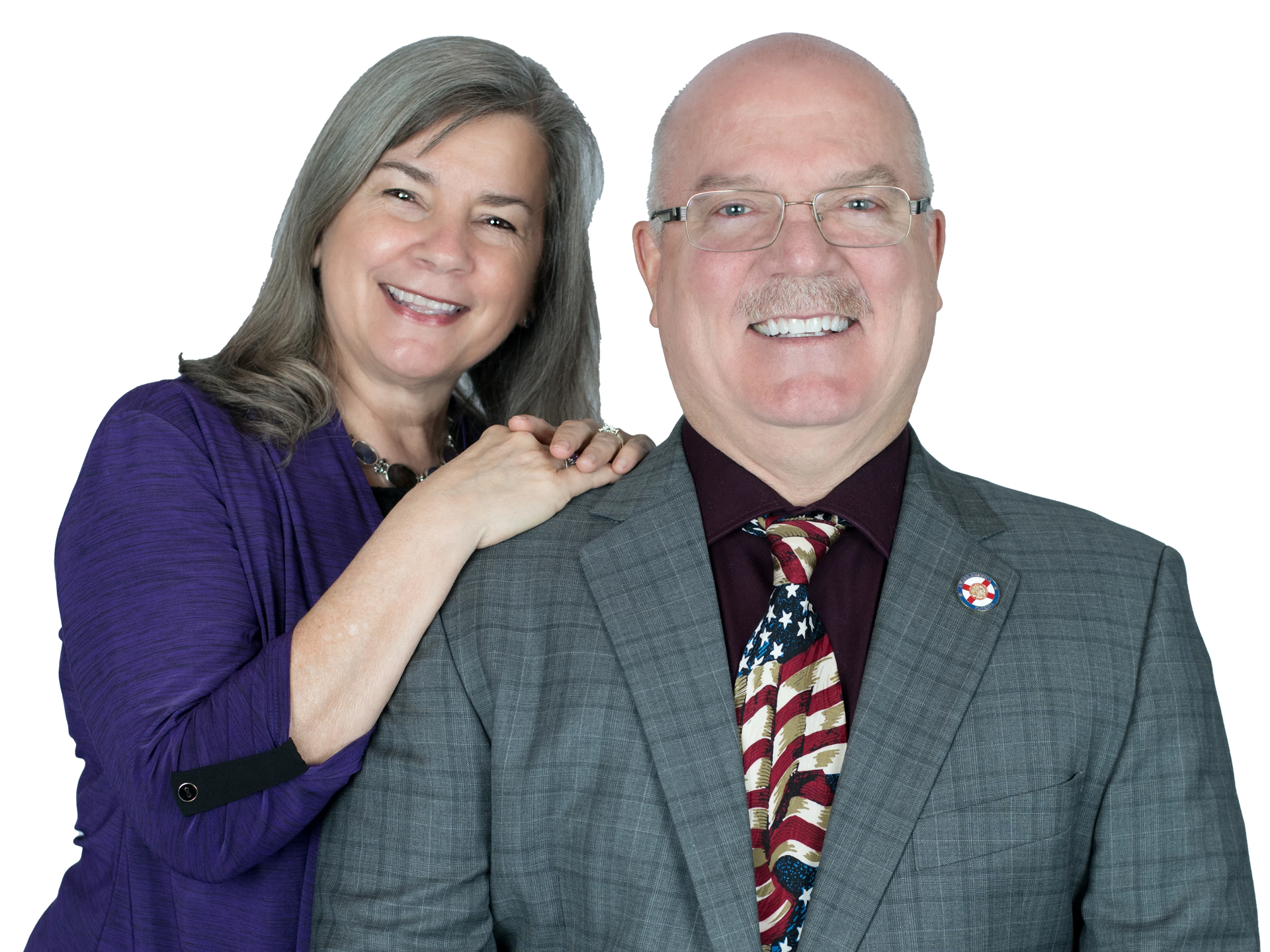 Two smiling people posing, one woman resting her hands on a man's shoulder, against a white background