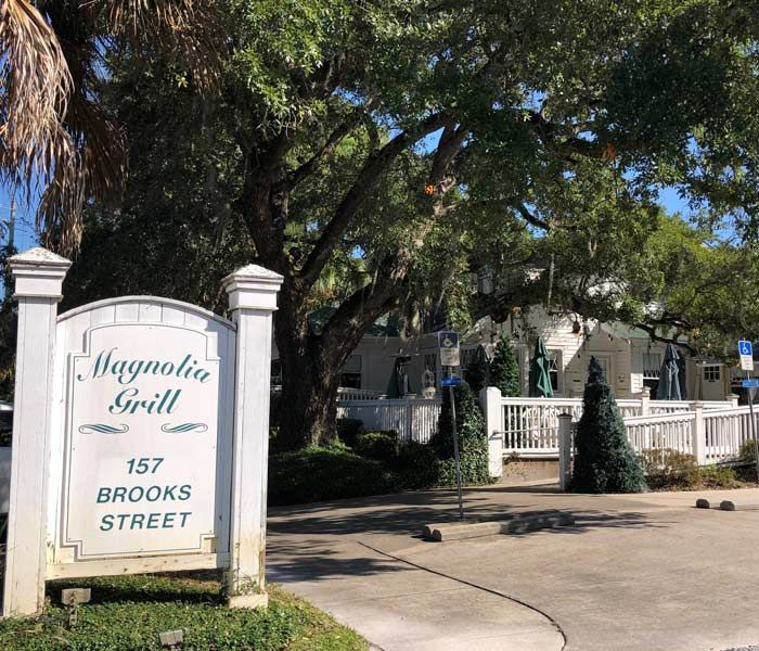 Magnolia Grill entrance sign at 157 Brooks Street beside a tree-lined driveway