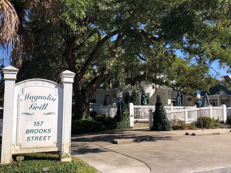 Magnolia Grill sign at 157 Brooks Street beside a white fence and driveway under trees