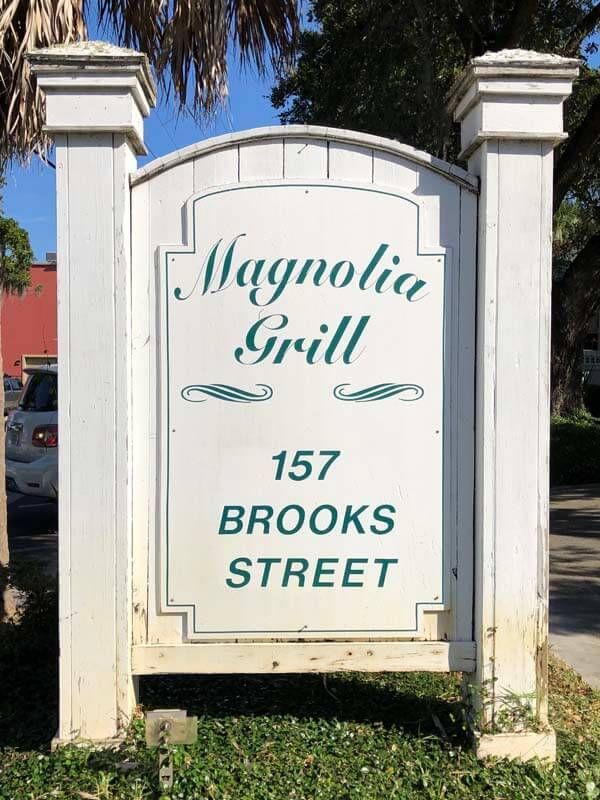 White sign for Magnolia Grill at 157 Brooks Street with teal lettering on a sunny day